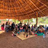 Unter einem Strohdach haben sich zwei Dutzend Bewohner von Muguramo, Südsambia, versammelt