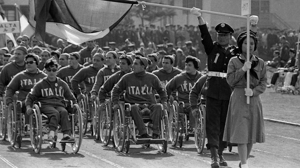 Eröffnungszeremonie: An den ab 1960 stattfindenden "Weltspielen der Gelähmten" nahmen zunächst ausschließlich Rollstuhlsportlerinnen und -sportler teil, hier 1964 in Tokio. 1988 erkannte das Internationale Olympische Komitee den Begriff "Paralympics" offiziell an