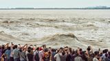 Leute, die die großen Wellen des Flusses Qiantang beobachten und fotografieren