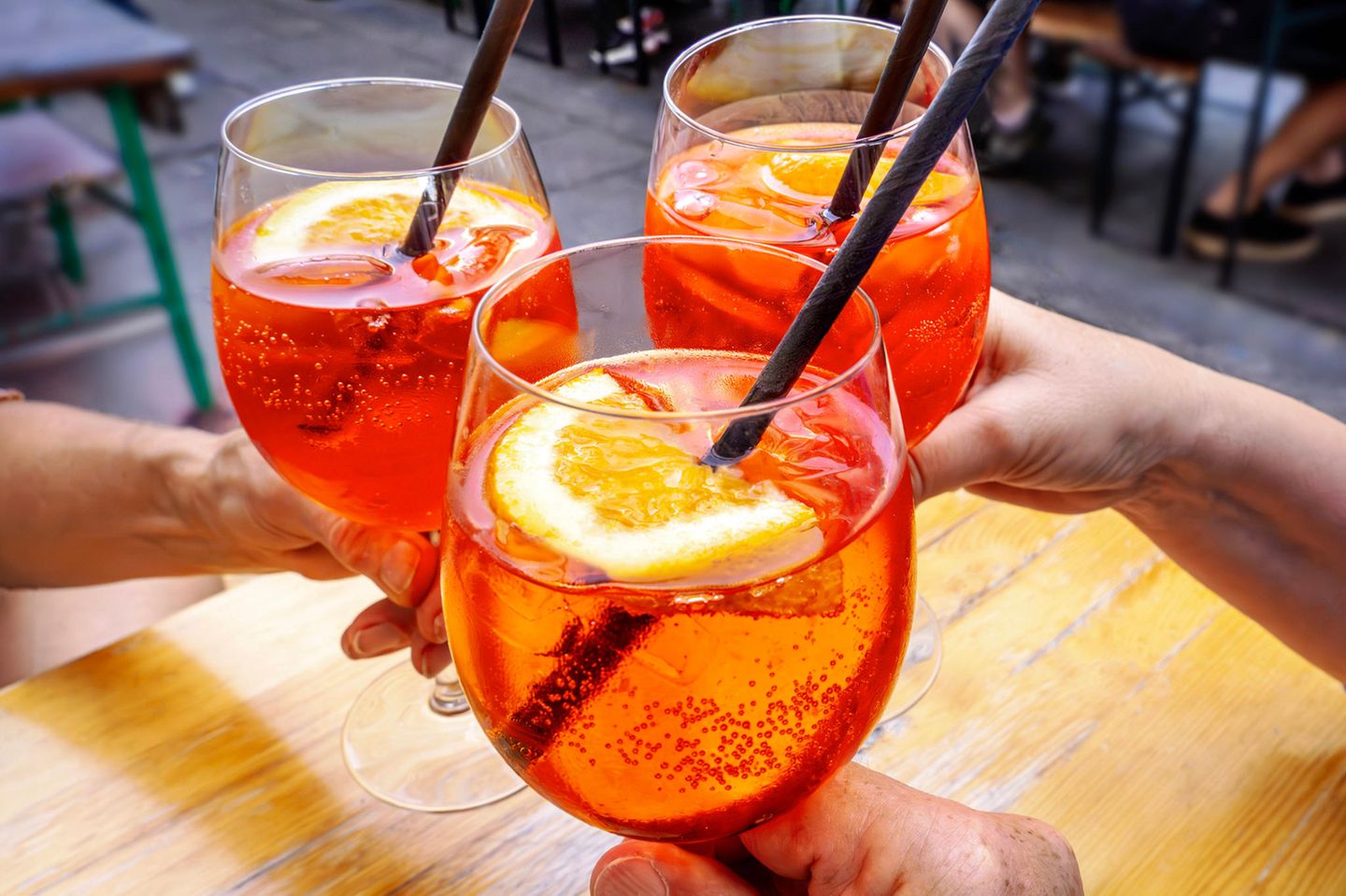 Azofarbstoffe: umstrittene Farbpracht Drei Gläser mit Aperol Spritz im Sonnenlicht