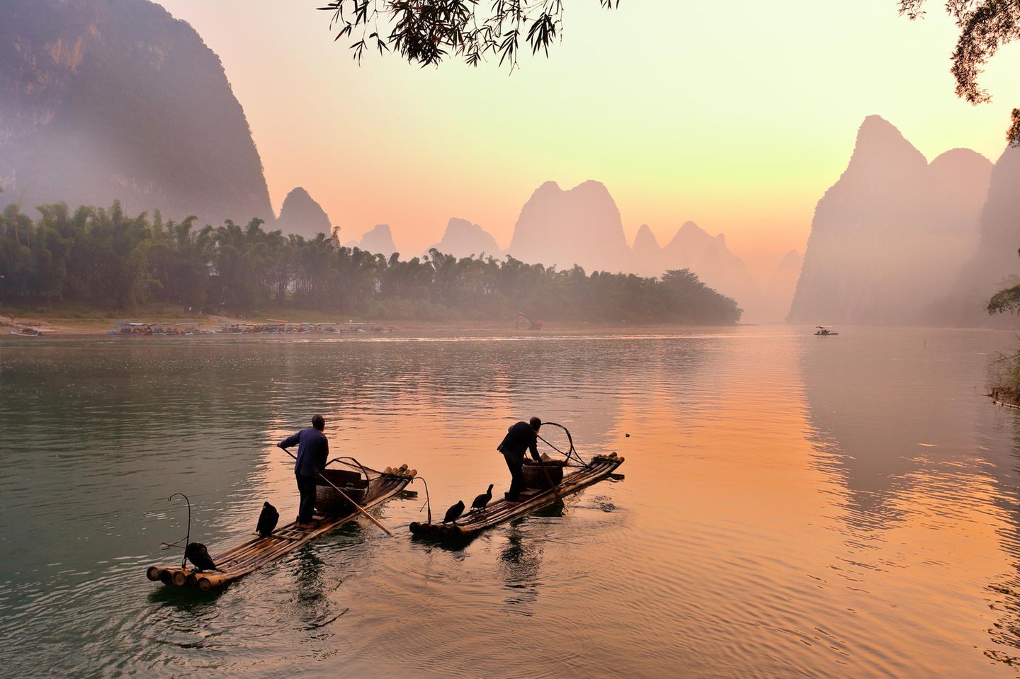 Silhouette zweier Fischer und seiner Kormorane am Li-Fluss bei Sonnenaufgang, Guilin, China