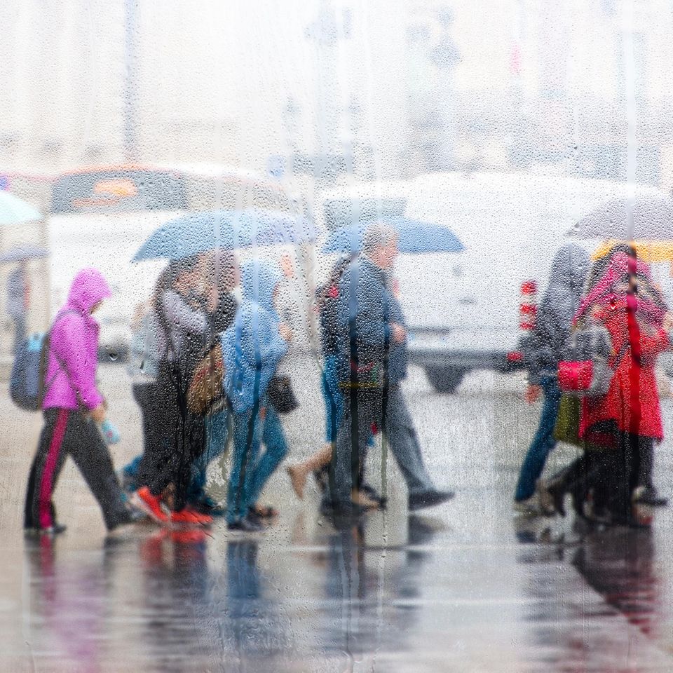 Menschen überqueren bei Regen die Straße
