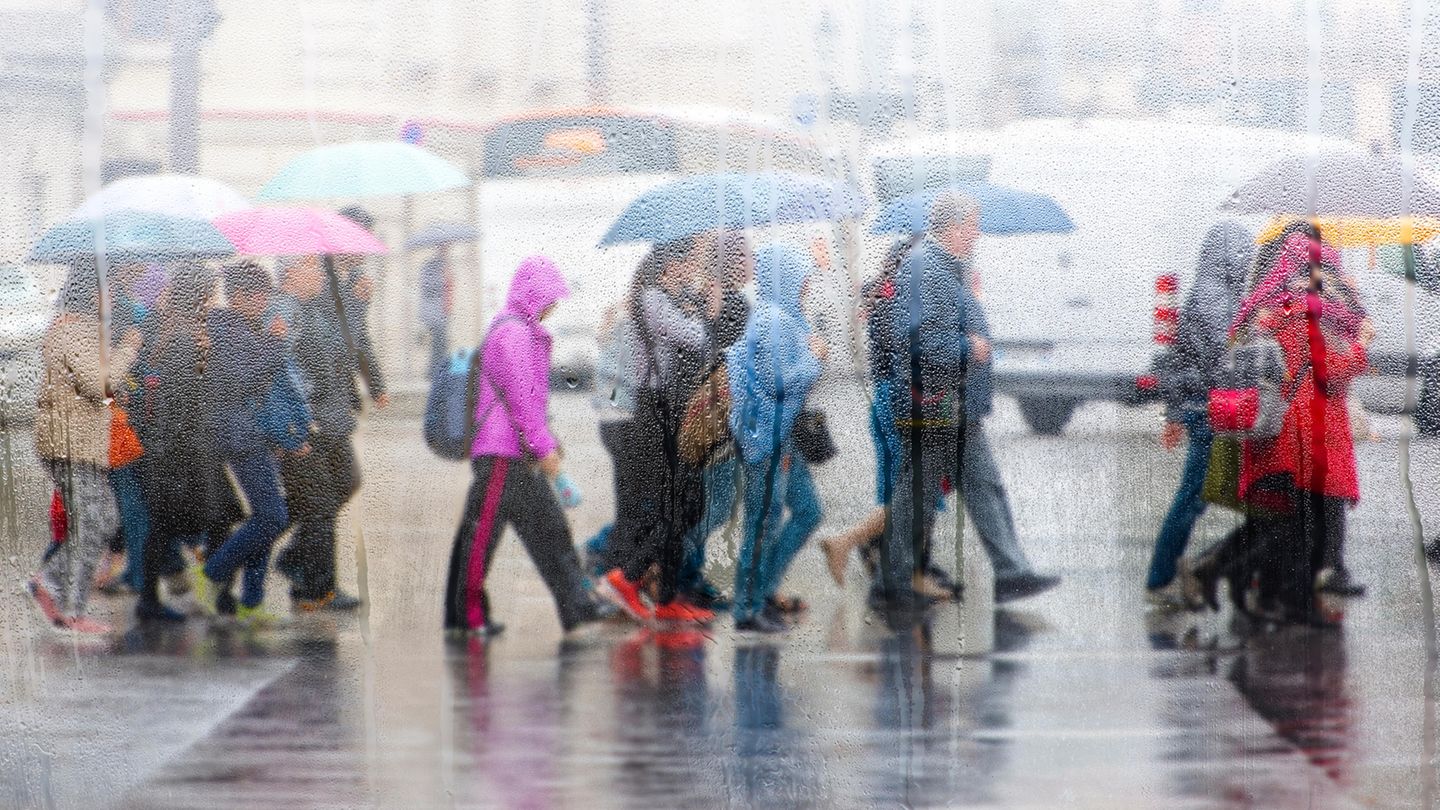 Menschen überqueren bei Regen die Straße