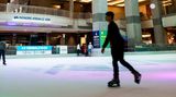 Menschen beim Eislaufen auf der Eisbahn mit der Kuppel darüber