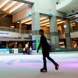 Menschen beim Eislaufen auf der Eisbahn mit der Kuppel darüber