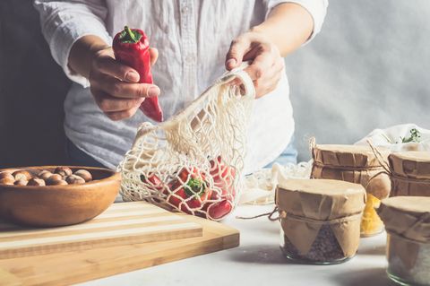 Eine Frau, der eine lange Paprika aus einem umweltfreundlichen Netz entfernt