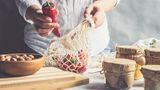 Eine Frau, der eine lange Paprika aus einem umweltfreundlichen Netz entfernt