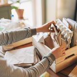 Hände, die Papiermaterialien in einer Holzkiste falten oder ausräumen