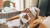 Hände, die Papiermaterialien in einer Holzkiste falten oder ausräumen