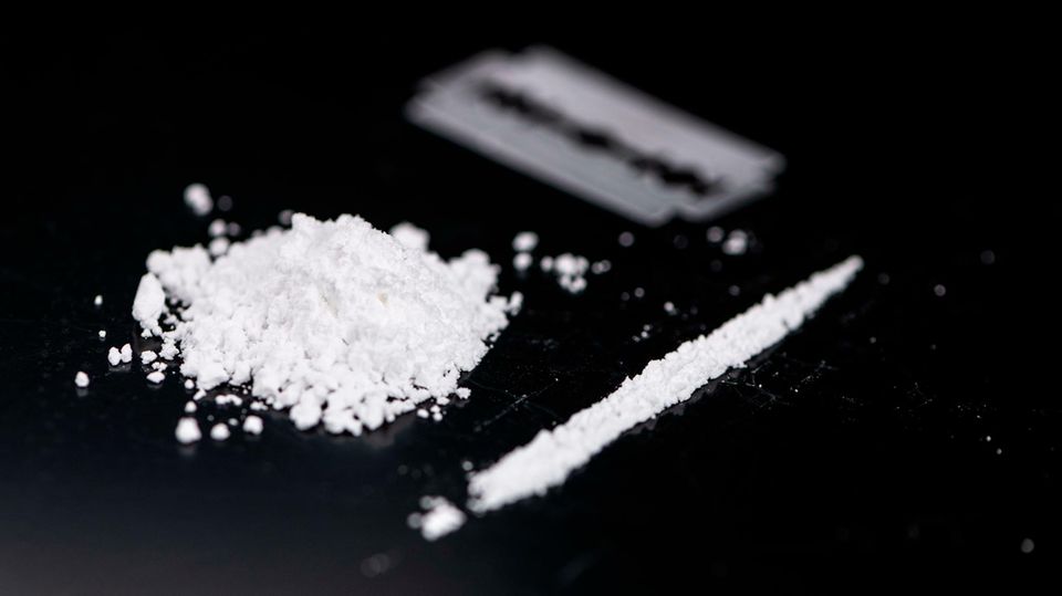 Kokainpulver neben einer Linie und im Hintergrund verschwommein eine Rasierklinge Kokainpulver neben einer Linie und im Hintergrund verschwommein eine Rasierklinge