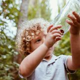 kleines Kind schaut sich an, was es in einem Glasgefäß gesammelt hat