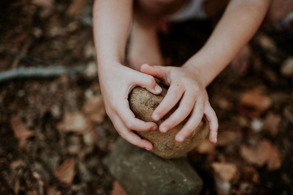 Vergrößert auf ein Kind, das mit Steinen spielt