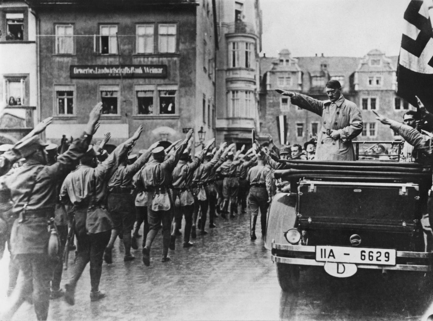 Adolf Hitler grüsst seine Soldaten aus einem offenen Auto heraus in Weimar
