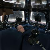 Don Pettit 2012 inmitten der Spiegelreflex-Kameras, die er in der "Cupola" montiert hat. Die Aussichtskuppel des Moduls Tranquility ist meist der Erdseite zugewandt. Viel zu sehen gibt es im Moment dieser Aufnahme allerdings nicht: Spezielle Fensterläden verdunkeln den Raum. Sie dienen unter anderem dem Schutz der Scheiben vor Mikrometeoriten. Eine Stoffabdeckung (unten) schirmt die Kuppel vom Rest der Raumstation ab.    