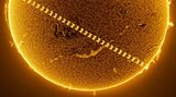 Durch die International Space Station (ISS). Den Transit der ISS über die Sonnenscheibe einzufangen sieht nicht nur spektakulär aus, es ist auch besonders schwer. Denn es ist nach 0,54 Sekunden wieder vorbei und weit von uns entfernt. Die ISS umkreist die Erde in 441,5 Kilometern Höhe. Noch mal über 100 Millionen Kilometer weiter weg befindet sich die Sonne. Miguel Claro schaffte es, den Moment einzufangen, in dem sich die Raumstation zwischen die beiden Himmelskörper schiebt. Dafür legte er 200 Bilder – innerhalb von zwei Sekunden geschossen – übereinander. Er nahm die Sequenz in Nordportugal Anfang Juni 2024 auf. Da war die ISS – sinnbildlich für die friedliche Zusammenarbeit seit den 1990er-Jahren – mit vier amerikanischen und drei russischen Astronauten besetzt.   KW 42