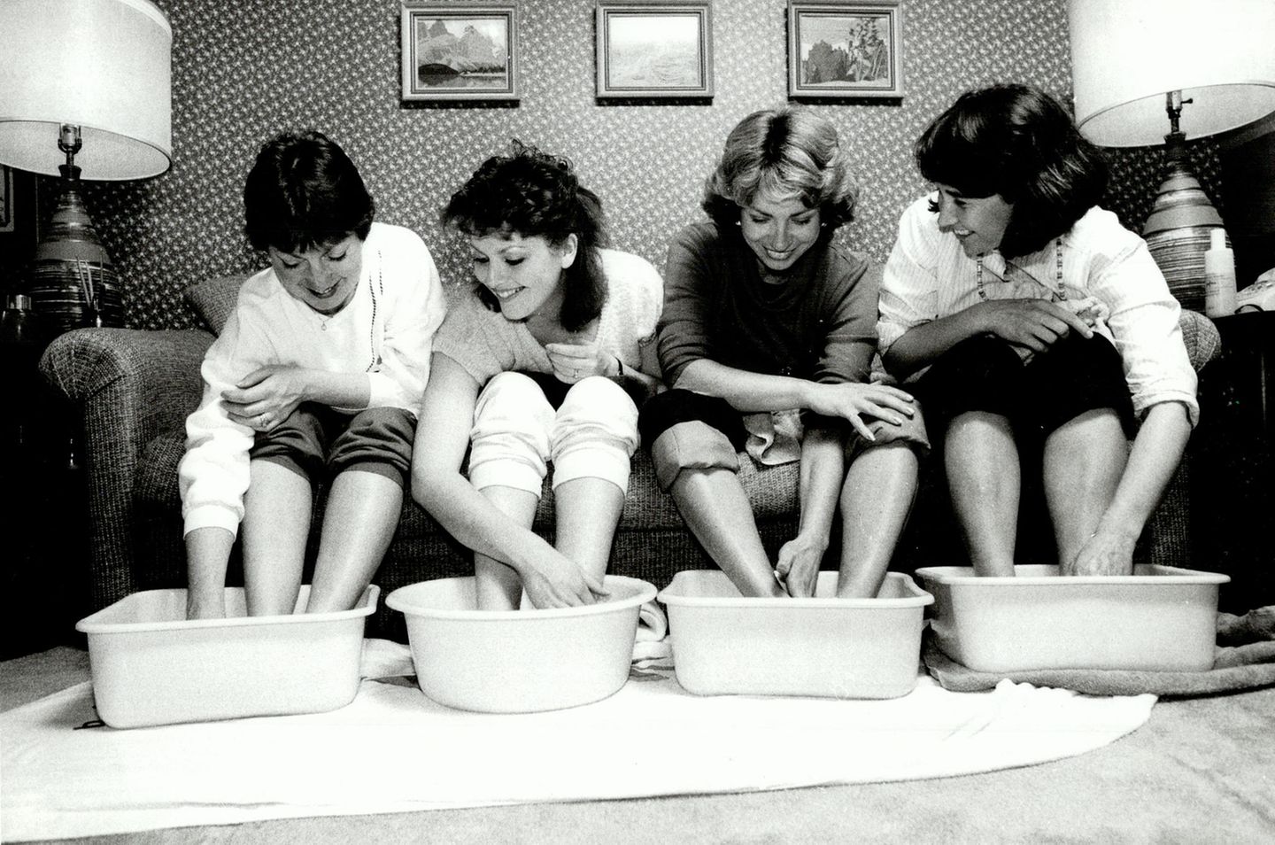 Vier Frauen baden lachend ihre Füße in Tupperschüsseln