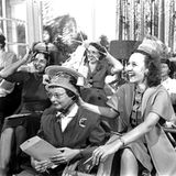 Lachende Frauen tragen zum Spaß Tupperschüsseln auf den Köpfen