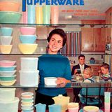 Eine Frau steht lächelnd vor Regalen voller bunter Tupperschüsseln