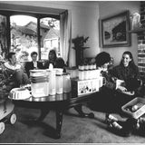 Um einen Tisch voller Tupperschüsseln sitzen Frauen und Kinder