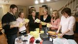Ein Mann und sechs Frauen begutachten Tupper-Produkte