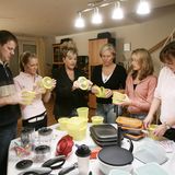 Ein Mann und sechs Frauen begutachten Tupper-Produkte