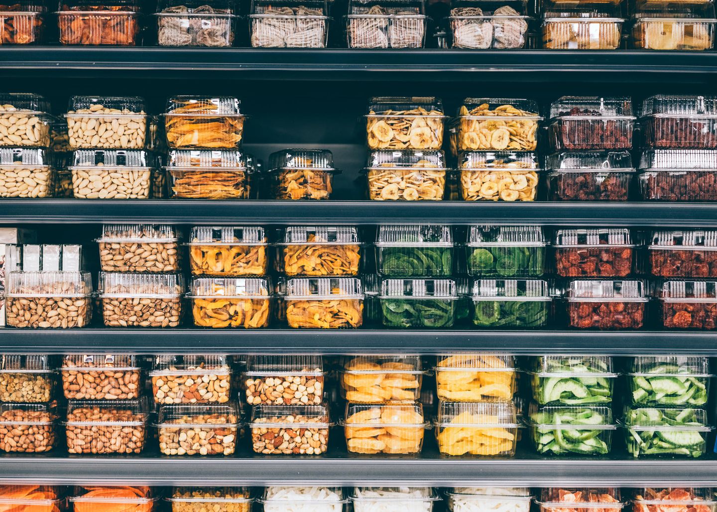 Lagern Sie Regale mit Trockenfrüchten, Gemüse und Nüssen in Plastikverpackungen