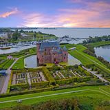Luftaufnahme eines Schlosses umgeben von Wasser und Grünanlagen
