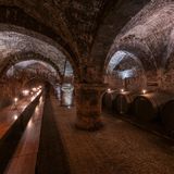 Hölzerne Weinfässer lagern, Tische und Bänke stehen im Weinkeller des Stiftungsweinguts Vereinigte Hospitien in Trier