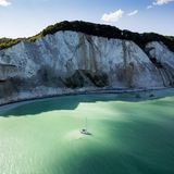 Ein Segelboot liegt vor den Møns Klint, der höchsten Steilküste Dänemarks vor Anker.