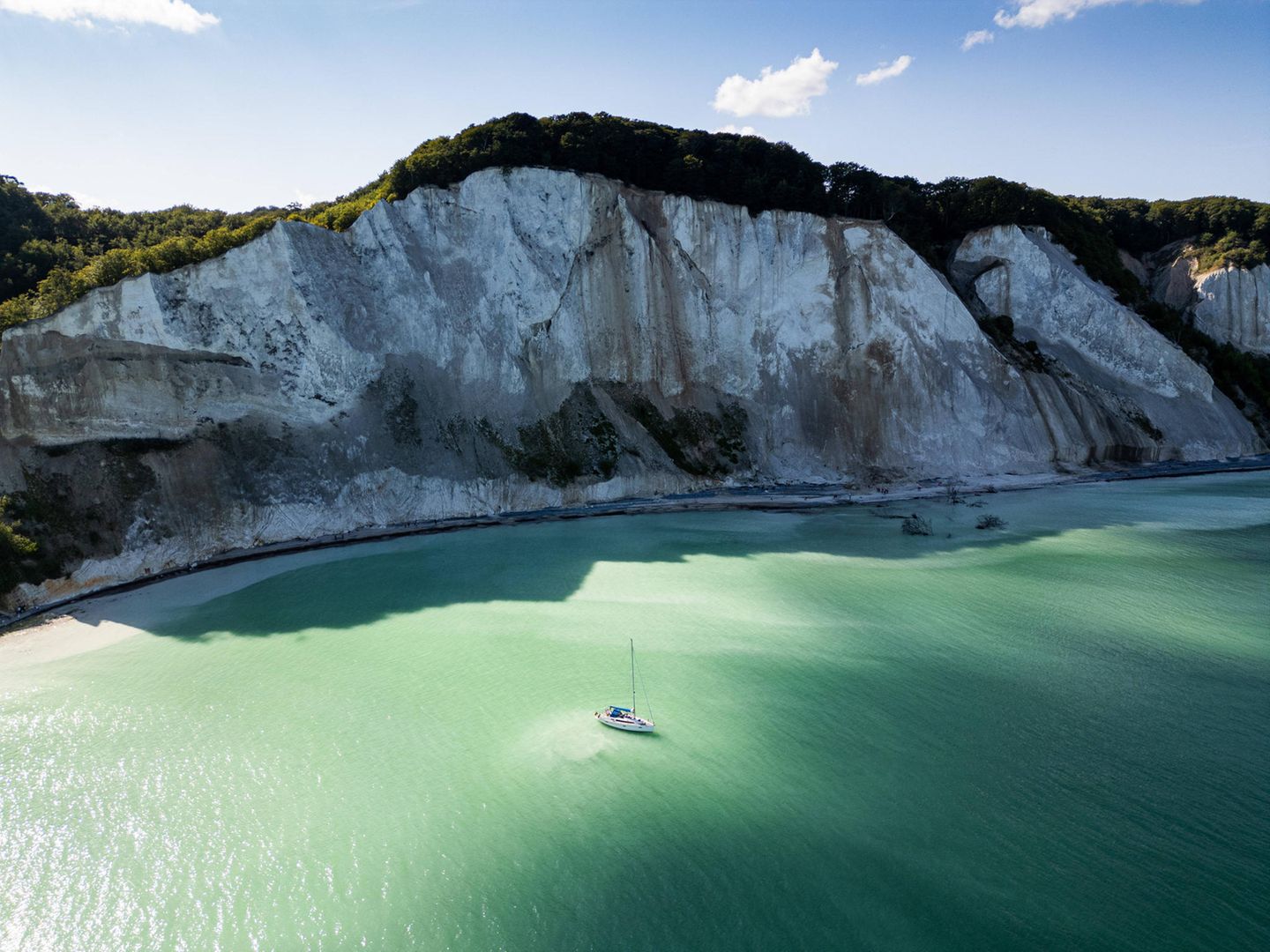 Møns Klint: der Kreidegigant Ein Segelboot liegt vor den Møns Klint, der höchsten Steilküste Dänemarks vor Anker.