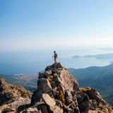 Mensch auf dem zackigen, felsigen Gipfel mit Blick auf das Meer