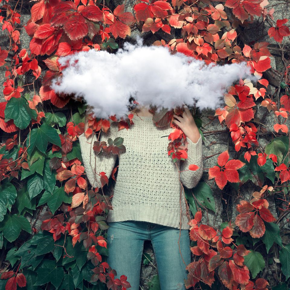 Frau vor roten Herbstblättern mit Wolke vor dem Gesicht