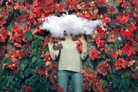 Frau vor roten Herbstblättern mit Wolke vor dem Gesicht