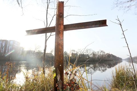 Metallkreuz steht am Wasser