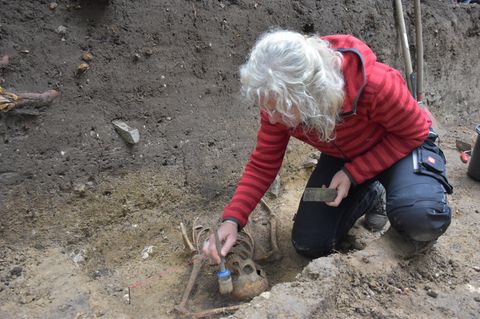 Frau legt Skelett in der Erde frei