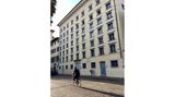 Mann auf Fahrrad vor gelbem Industriehaus