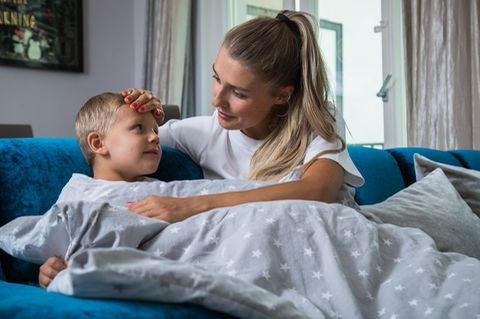 Mutter hält krankem Sohn die Stirn