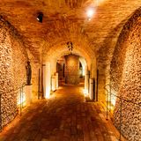 Beleuchtetes Gewölbe mit Knochen- und Schädelstapel entlang der Wände