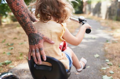 Vater hilft Tochter beim Dreiradfahren