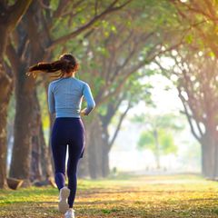 Frau joggt eine Allee entlang