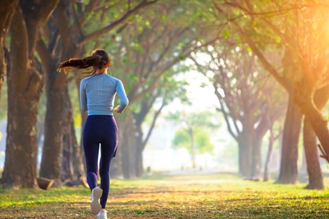 Frau joggt eine Allee entlang