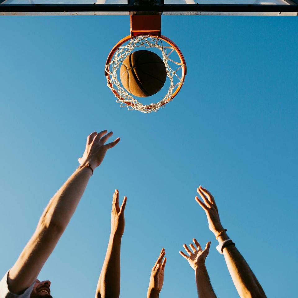 Hände werfen einen Basketball in einen Korb