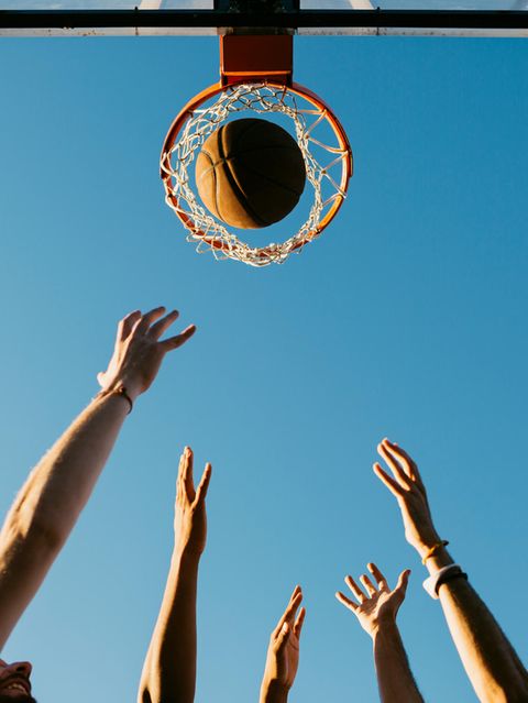 Hände werfen einen Basketball in einen Korb