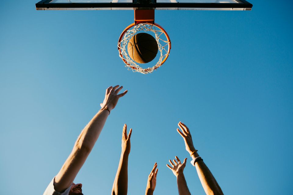 Hände werfen einen Basketball in einen Korb 1.5004