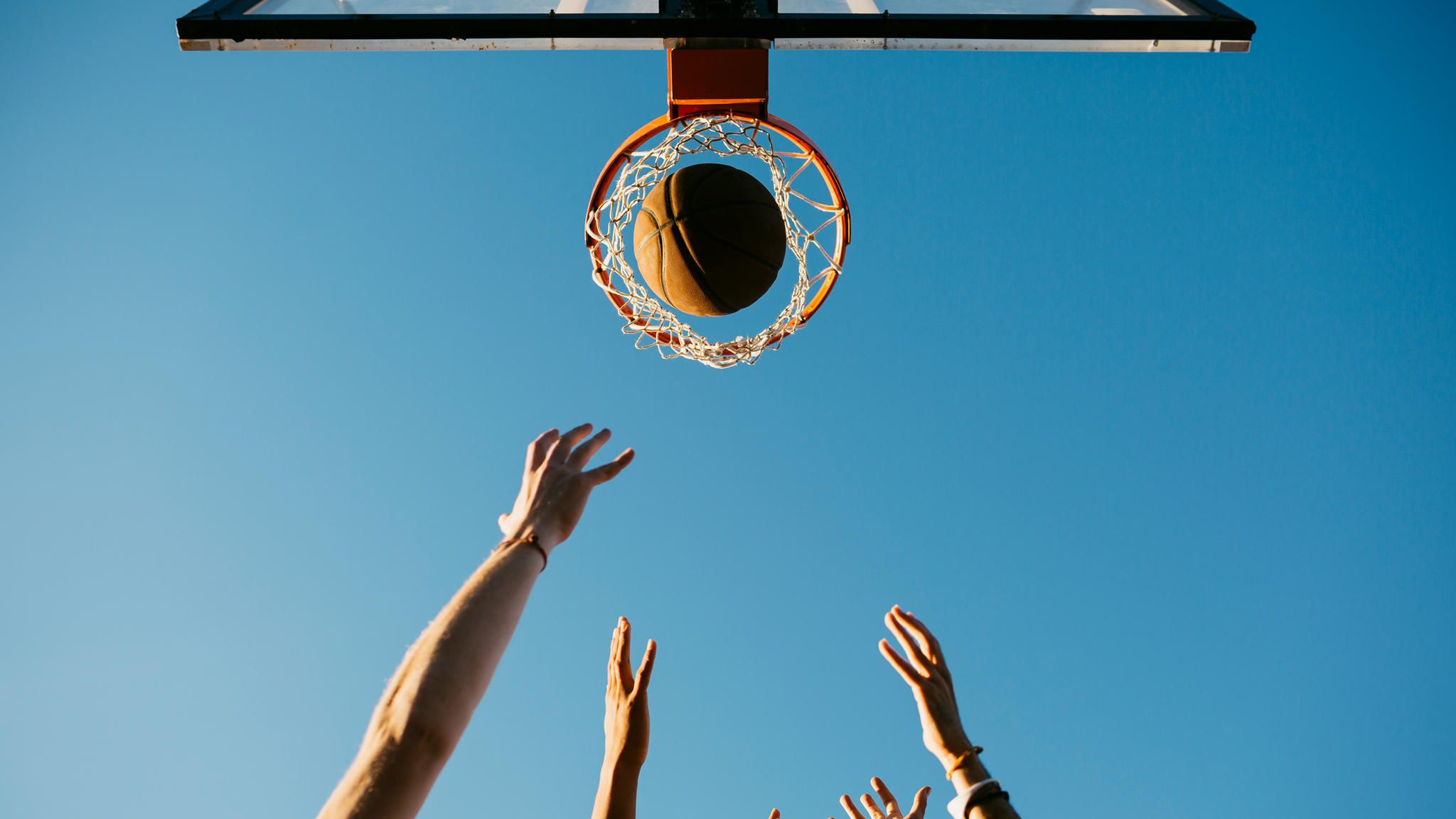 Hände werfen einen Basketball in einen Korb