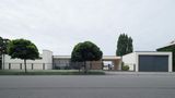 Bungalow mit großen Fenstern und Bäumen davor, Straßenansicht