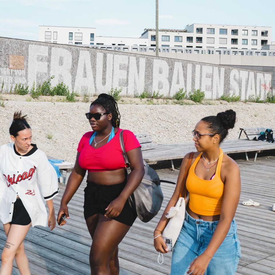Drei Frauen laufen vor Schriftzug "Frauen bauen Stadt"