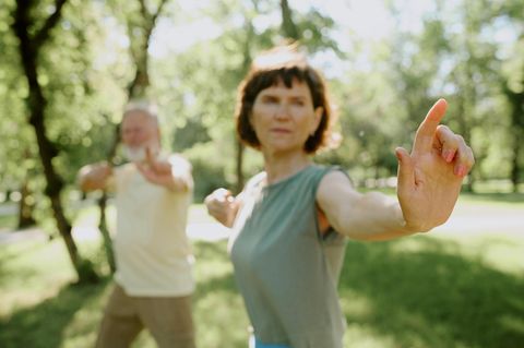 Eine ältere Frau und ein älterer Mann praktizieren Qigong