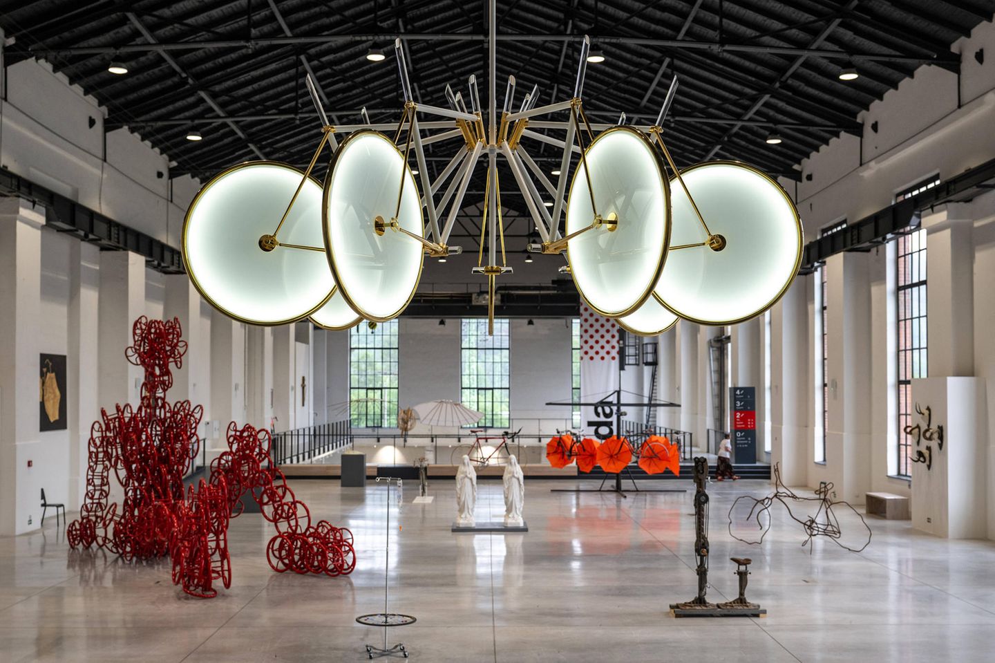 Lichtskulptur hängt an der Decke einer großen Maschinenhalle