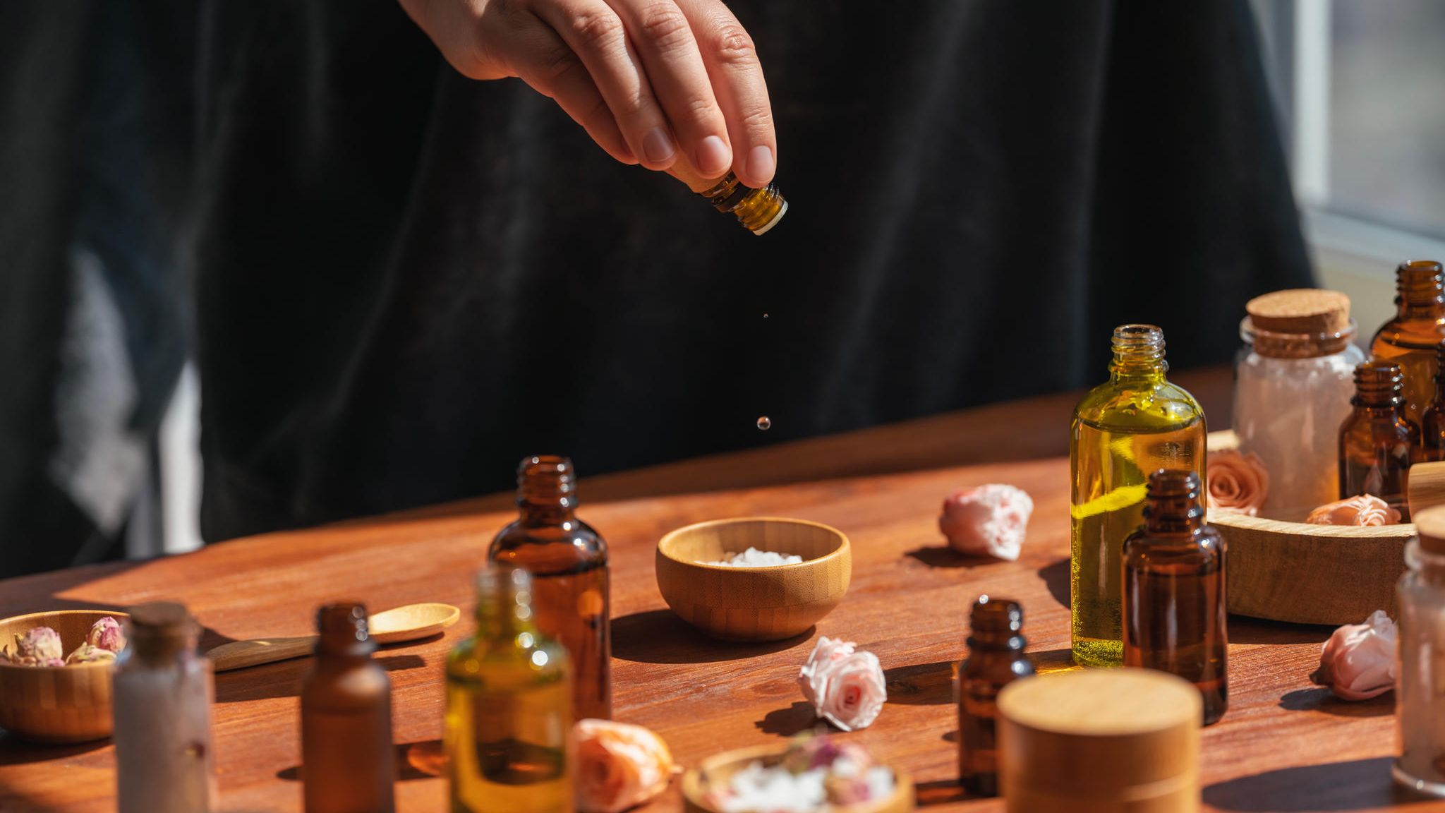 Hand träufelt Tropfen in eine mit Salz gefüllte Schale. Drum herum stehen diverse weitere Tinkturen Hand träufelt Tropfen in eine mit Salz gefüllte Schale. Drum herum stehen diverse weitere Tinkturen